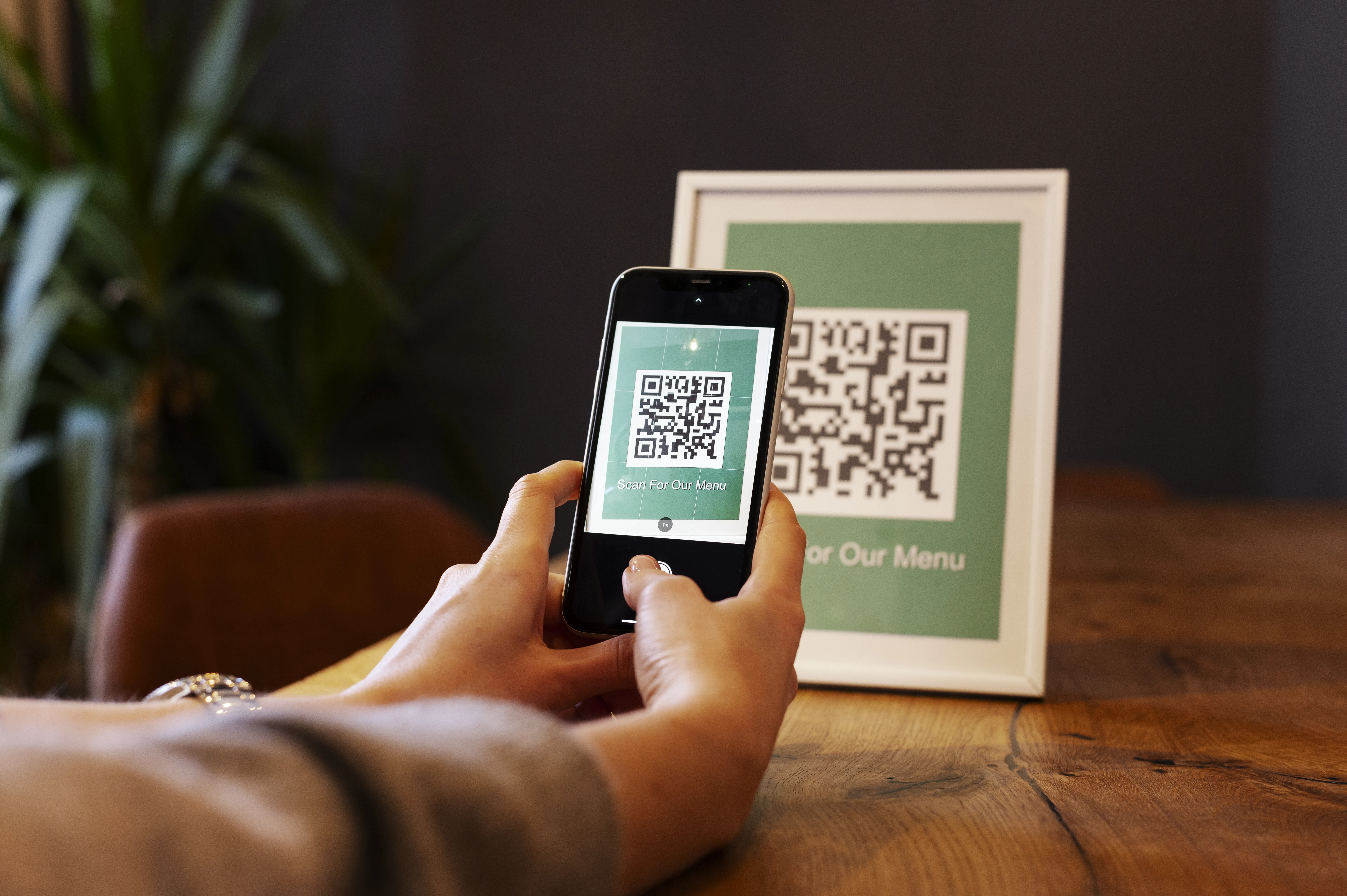 A woman holding a credit card and a smartphone in a cozy cafe